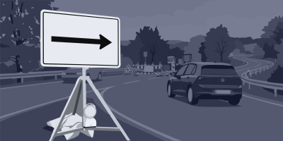 Ein weißes Verkehrsschild mit schwarzem Pfeil nach rechts steht auf einem Dreibein-Ständer am Rand einer Landstraße; im Hintergrund fährt ein dunkler Kompaktwagen von hinten gesehen nach rechts, dahinter eine Baustelle mit Absperrgittern, Warnbaken und einem Gefahrenzeichen zwischen Bäumen.